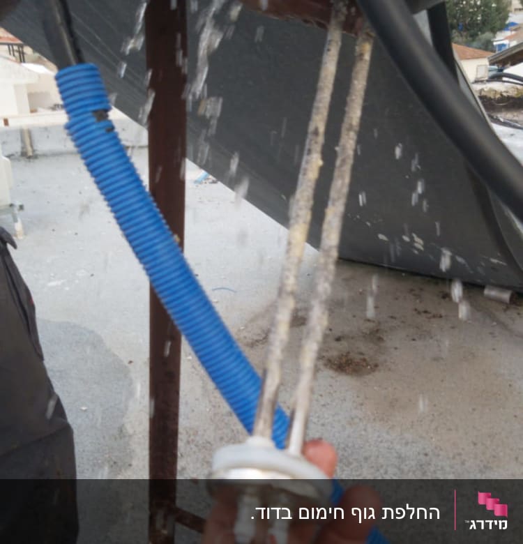 יד מחזיקה גוף חימום של דוד שמש עם מים זורמים